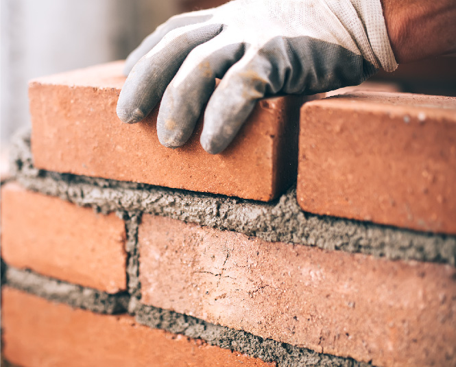 Construction worker's hands laying bricks.